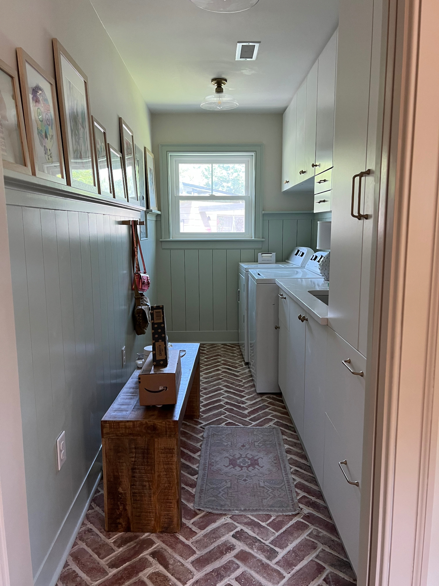 Custom laundry room with painted millwork and brick floor